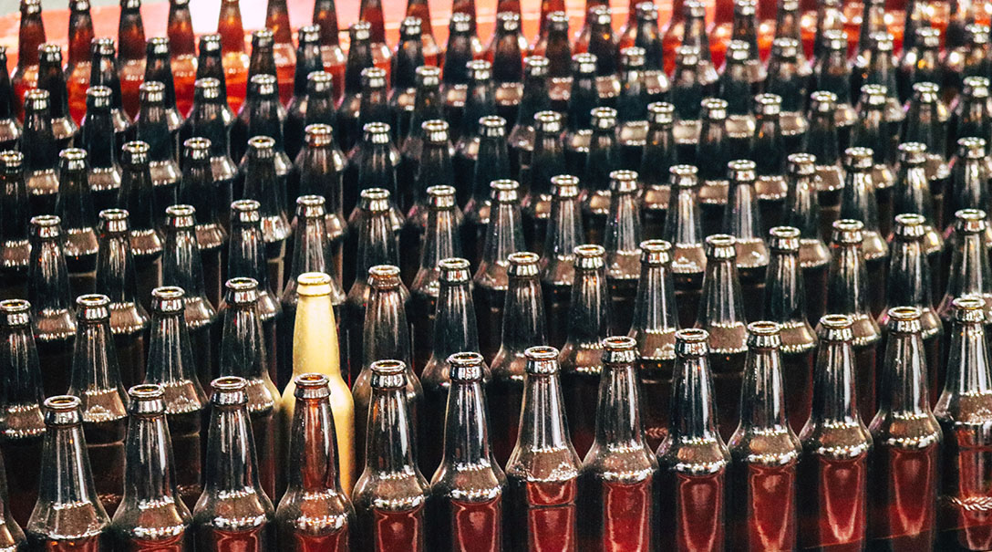 Meerdere rijen van glazen flesjes waartussen een gouden flesje die opvalt, dit is een metafoor voor de positionering van een product op de markt.